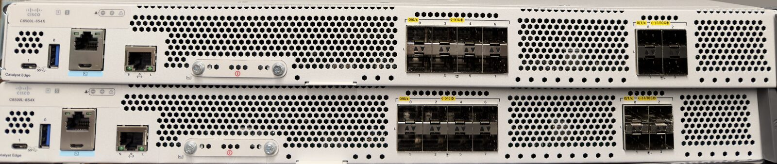Front view of two stacked Cisco Catalyst Edge routers showing their management, console and USB ports and rows of SFP and SFP+ fiber ports